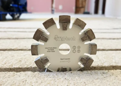 Tarcza diamentowa do frezowania betonu marki TM-tech, leżąca na chropowatej powierzchni, z widocznymi segmentami szlifierskimi i parametrami technicznymi.