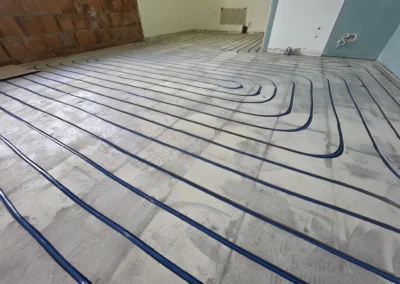 System ogrzewania podłogowego z niebieskimi rurami ułożonymi w jastrychu cementowym na dużej powierzchni